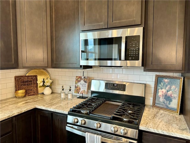 kitchen featuring backsplash, dark brown cabinetry, light stone counters, and appliances with stainless steel finishes