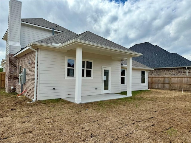 back of house with a patio and a lawn