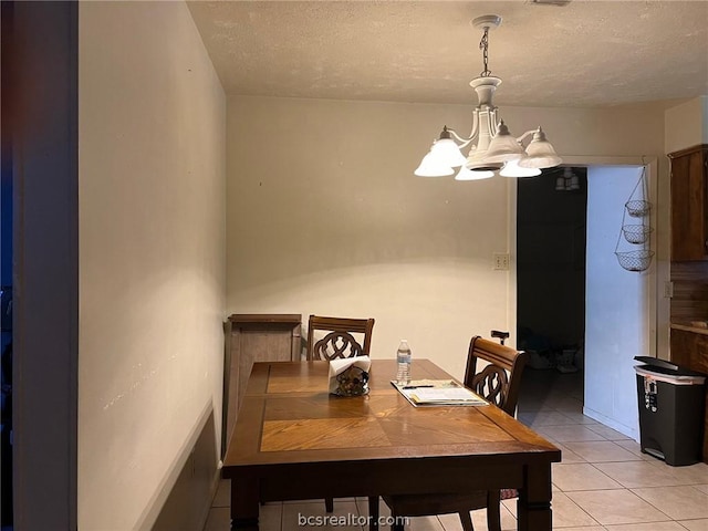 dining space featuring light tile patterned floors, a textured ceiling, and a notable chandelier