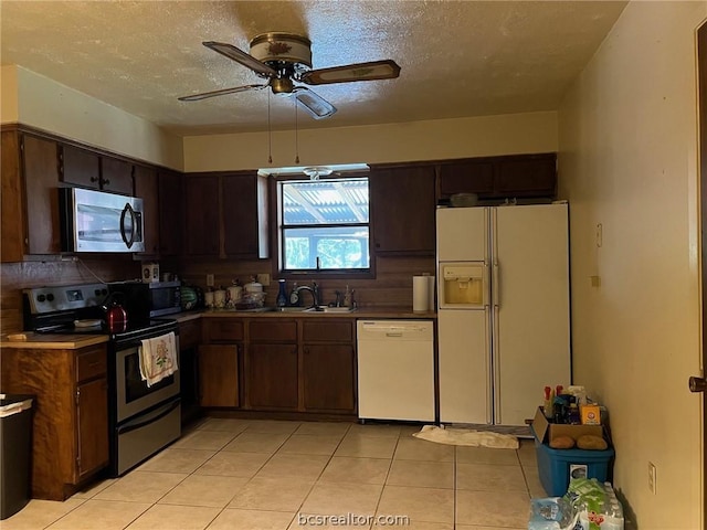 kitchen featuring appliances with stainless steel finishes, a textured ceiling, dark brown cabinetry, sink, and light tile patterned flooring