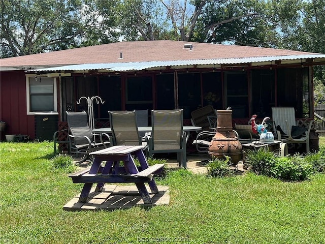 rear view of property featuring a fire pit and a lawn