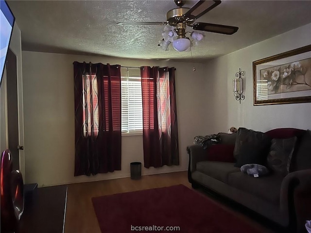 living room featuring ceiling fan and a textured ceiling