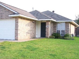 single story home with a garage, brick siding, and a front lawn