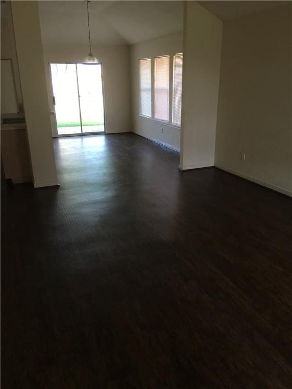 spare room with baseboards and dark wood-type flooring