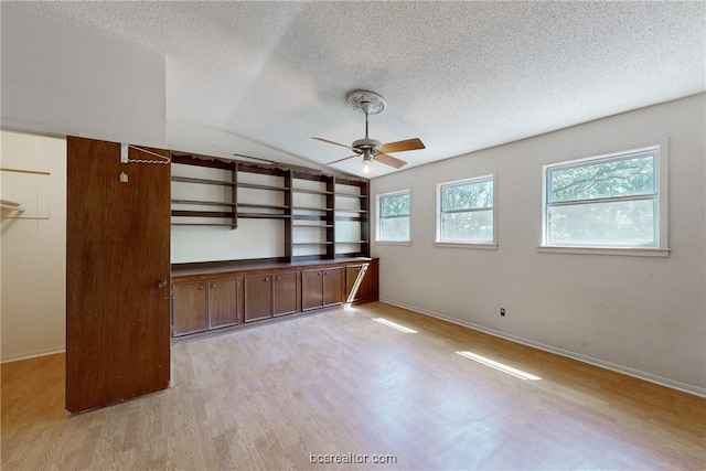 interior space featuring a textured ceiling, ceiling fan, light hardwood / wood-style floors, and vaulted ceiling