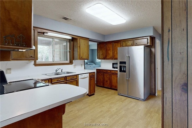 kitchen featuring dishwasher, stainless steel fridge, a textured ceiling, and sink