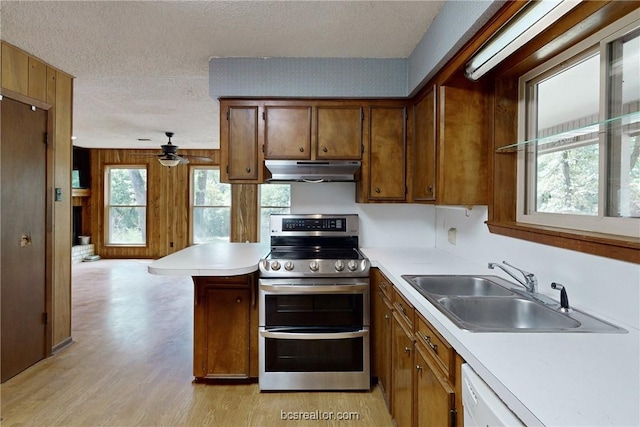 kitchen with sink, stainless steel stove, ceiling fan, a textured ceiling, and a wealth of natural light