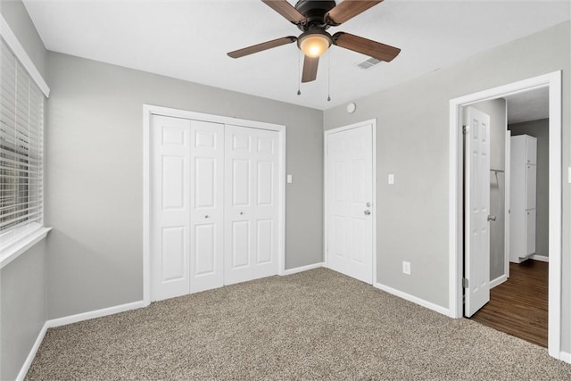 unfurnished bedroom with a closet, dark carpet, and ceiling fan