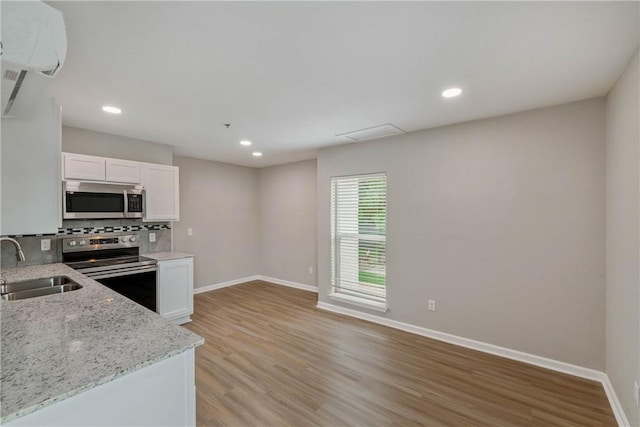615 San Jacinto Ln, Bryan, TX 77803 - kitchen featuring stainless steel appliances, white cabinetry, light stone countertops, light wood-style floors, and decorative backsplash