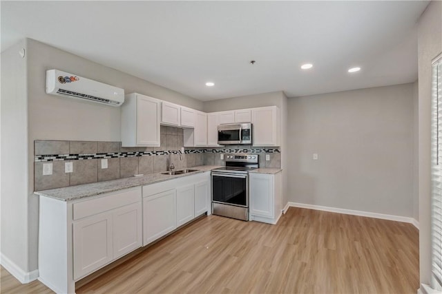 615 San Jacinto Ln, Bryan, TX 77803 - kitchen featuring stainless steel appliances, a wall unit AC, light wood-type flooring, tasteful backsplash, and recessed lighting