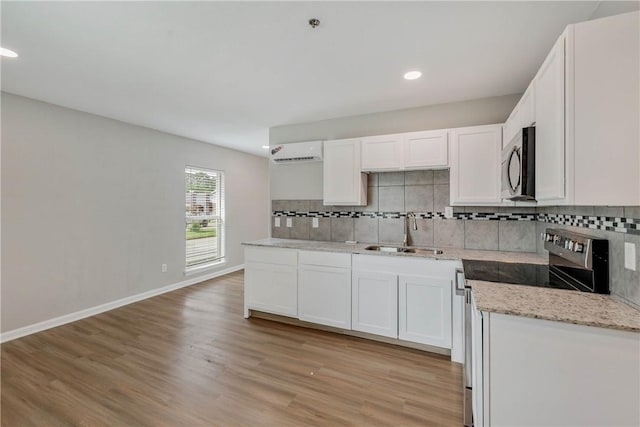 615 San Jacinto Ln, Bryan, TX 77803 - kitchen featuring stainless steel appliances, a wall mounted air conditioner, light wood-type flooring, backsplash, and recessed lighting
