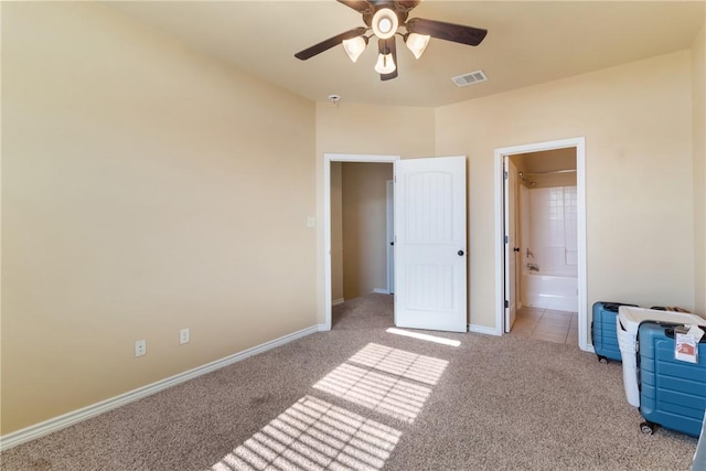 bedroom featuring ceiling fan, light colored carpet, and connected bathroom