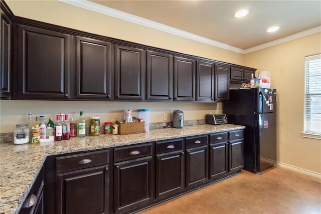 kitchen featuring crown molding, dark brown cabinetry, black fridge, and light stone countertops