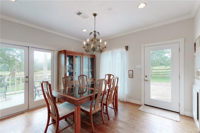 dining space featuring an inviting chandelier, ornamental molding, light hardwood / wood-style flooring, and french doors