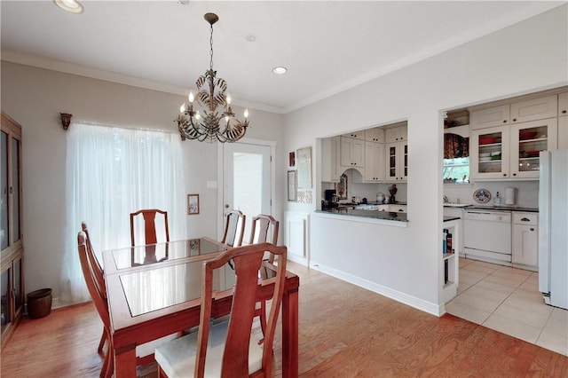 dining area featuring crown molding, a chandelier, and light wood-type flooring