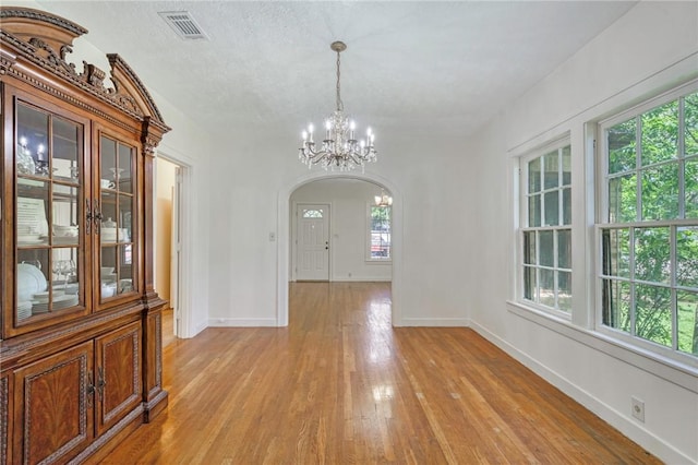 409 N Hutchins St, Bryan, TX 77803 - unfurnished dining area featuring a chandelier, light wood-style flooring, and arched walkways
