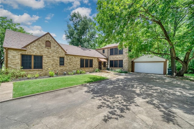 409 N Hutchins St, Bryan, TX 77803 - view of front facade featuring an outbuilding, a front lawn, concrete driveway, stone siding, and a shingled roof