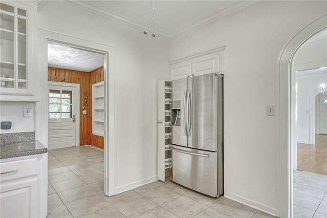 409 N Hutchins St, Bryan, TX 77803 - kitchen with stainless steel fridge, white cabinets, wood walls, glass insert cabinets, and ornamental molding