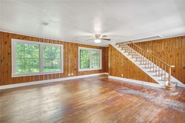 409 N Hutchins St, Bryan, TX 77803 - unfurnished living room with wood-type flooring, stairs, a ceiling fan, and wooden walls