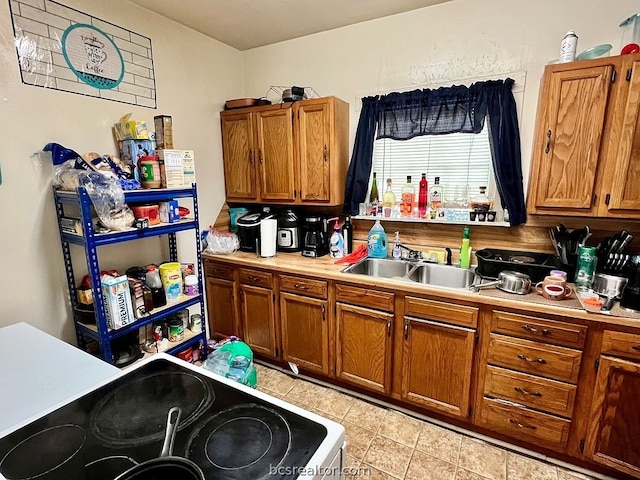 kitchen with sink, light tile patterned floors, and stove