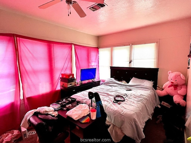 bedroom with ceiling fan, carpet floors, and a textured ceiling