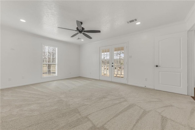 empty room with light carpet, crown molding, french doors, and ceiling fan