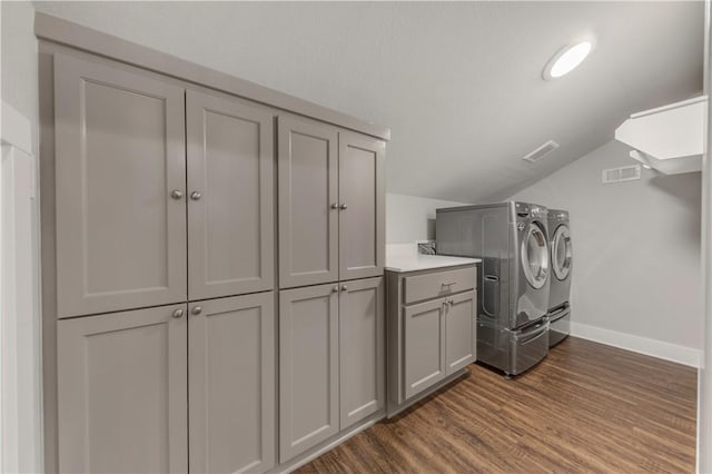 laundry area with dark hardwood / wood-style flooring, cabinets, and washer and dryer