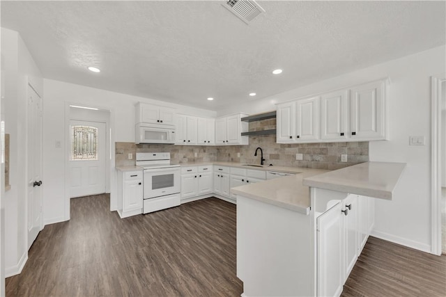 kitchen featuring white appliances, dark hardwood / wood-style floors, kitchen peninsula, and white cabinets