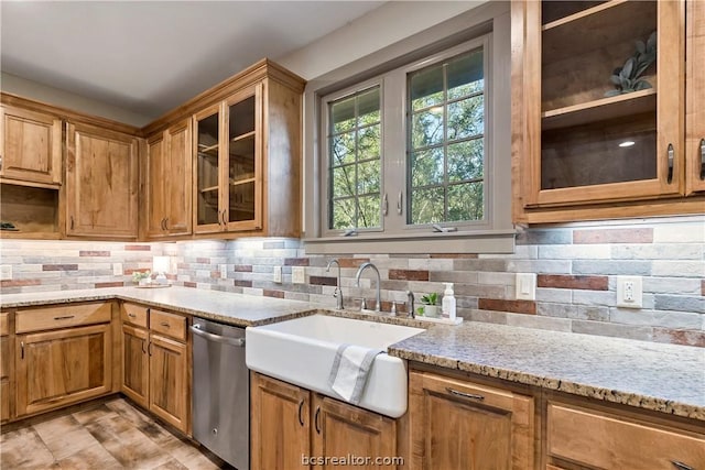 kitchen with dishwasher, decorative backsplash, light stone counters, and sink