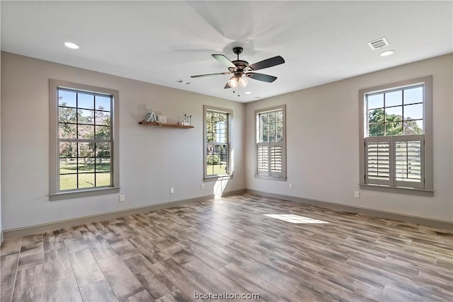 spare room with light wood-type flooring, a wealth of natural light, and ceiling fan