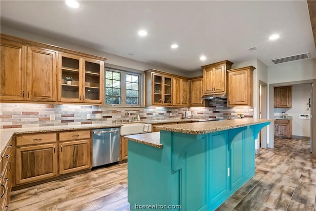 kitchen with tasteful backsplash, light hardwood / wood-style flooring, dishwasher, a center island, and a breakfast bar area