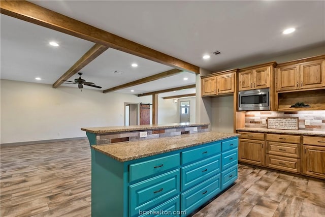 kitchen featuring a center island, light hardwood / wood-style floors, stainless steel microwave, and stone countertops