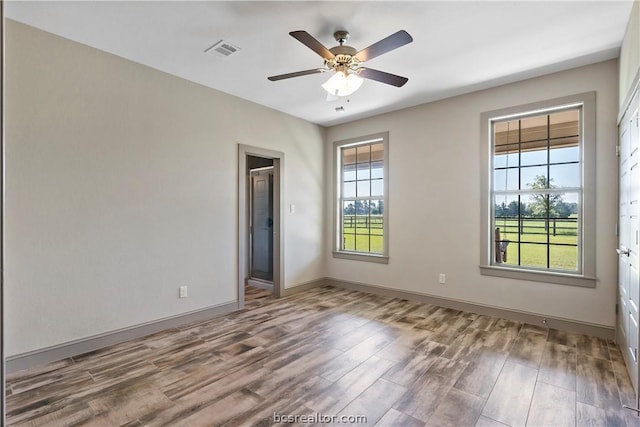 spare room with wood-type flooring, ceiling fan, and a healthy amount of sunlight