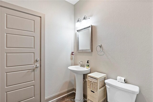 bathroom with hardwood / wood-style flooring, toilet, and sink