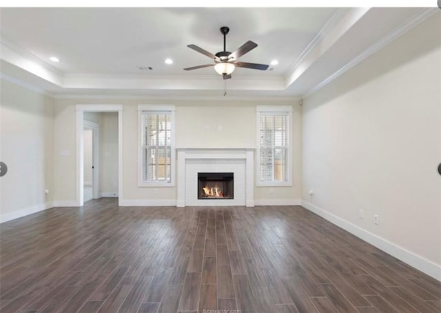 unfurnished living room with a raised ceiling, dark wood-style floors, and ceiling fan