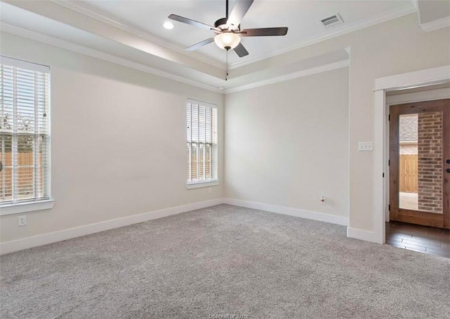 carpeted empty room with visible vents, baseboards, ornamental molding, a ceiling fan, and a raised ceiling