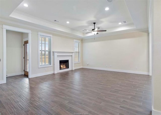 unfurnished living room with a raised ceiling, visible vents, ceiling fan, and wood finished floors