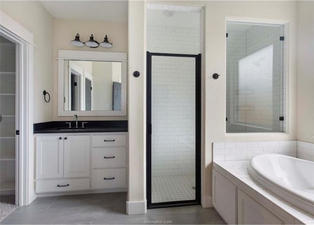 full bath featuring tile patterned floors, vanity, a garden tub, and a shower stall