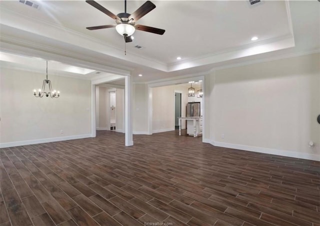 unfurnished living room featuring a tray ceiling, ornamental molding, ceiling fan with notable chandelier, and dark wood finished floors