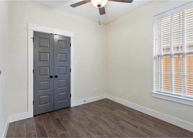 interior space featuring baseboards, dark wood-type flooring, and a ceiling fan
