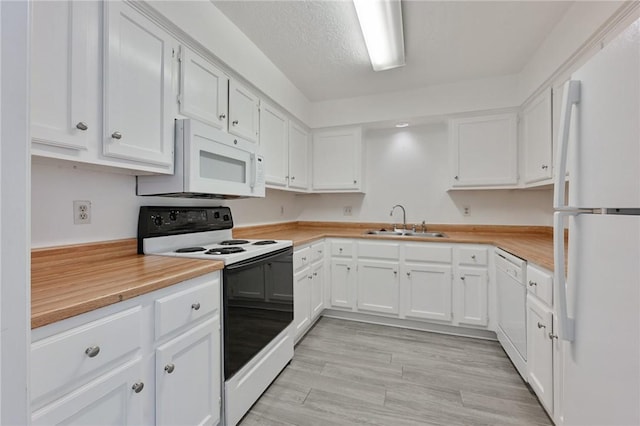 kitchen with white appliances, white cabinetry, light countertops, and a sink