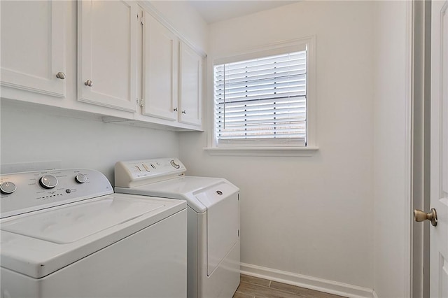 washroom with cabinet space, baseboards, washer and dryer, and wood finished floors