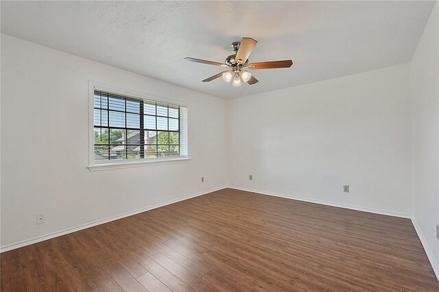 unfurnished room featuring dark wood-style floors, baseboards, and a ceiling fan