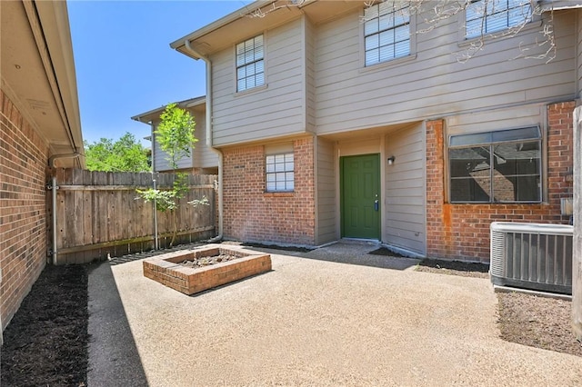 view of exterior entry featuring a patio area, fence, central AC, and brick siding