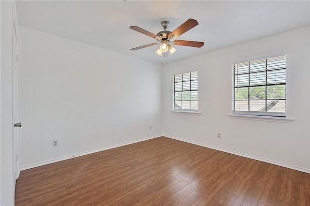 empty room with a healthy amount of sunlight, baseboards, and wood finished floors