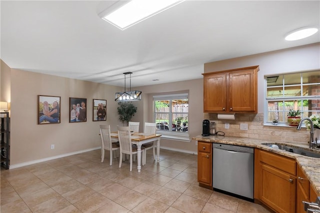 kitchen featuring baseboards, brown cabinetry, dishwasher, and a sink