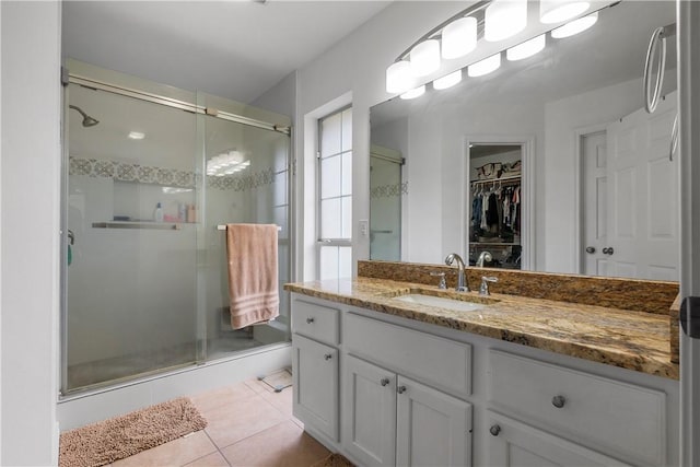 bathroom with tile patterned floors, a spacious closet, a shower stall, and vanity
