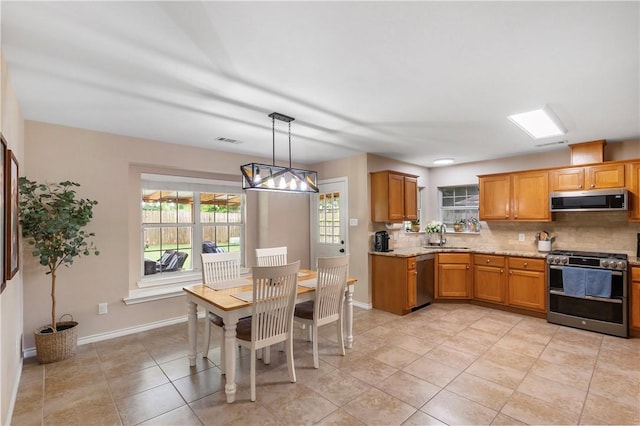 kitchen with a sink, appliances with stainless steel finishes, visible vents, baseboards, and backsplash