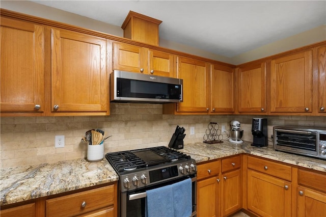 kitchen featuring appliances with stainless steel finishes, a toaster, and brown cabinetry