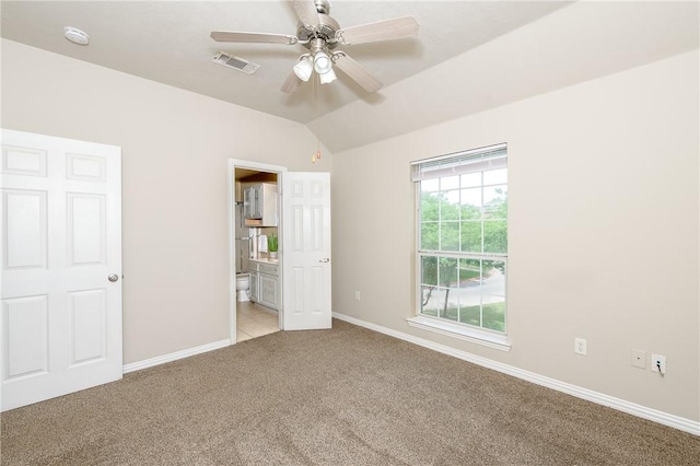 unfurnished bedroom with lofted ceiling, visible vents, light carpet, ensuite bath, and baseboards